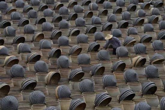  ▲传统酿造酱油讲究“春曲、夏酱、秋油”，利用自然地温度变化，经过“日晒夜露”制作，因此速度很慢，少则数月多则以年计算。图为正在进行酿晒的酱油缸（图片来自网络）